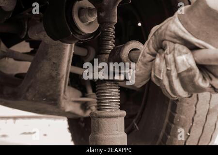 Reifenservice, Car Service Konzept. Hand in Handschuh hebt das Fahrzeug mit einem mechanischen Wagenheber an. Ersetzen eines Platten Reifens. Selektiver Fokus. Stockfoto