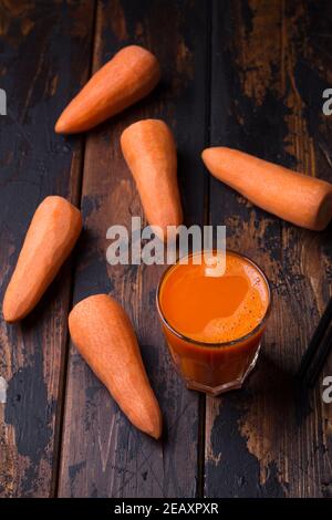 Frischer Karottensaft im Glas auf dunklem Holzhintergrund, Draufsicht Stockfoto