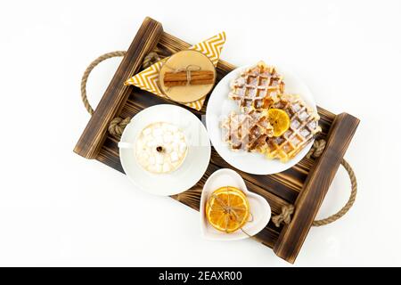 Frühes Frühstück Kaffee mit Marshmallows und einem Stock Zimt Und belgische Waffeln liegen auf einem Holztablett Stockfoto