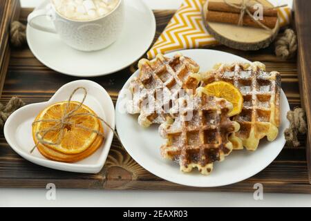 Frühes Frühstück Kaffee mit Marshmallows und einem Stock Zimt Und belgische Waffeln liegen auf einem Holztablett Stockfoto