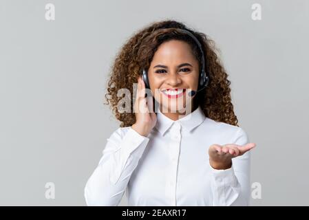 Porträt von glücklich lächelnd fröhlich afroamerikanischen Frau Kunden-Support Telefonhörer im Headset auf grauem Hintergrund Stockfoto