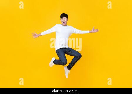 Junge glücklich koreanische teen springen willkommen isoliert auf gelben Studio Hintergrund Stockfoto