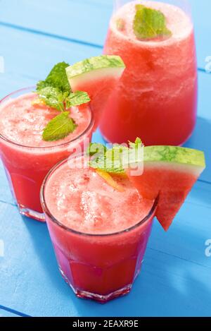 Kalte, erfrischende, tropische Wassermelonen-Getränke im Sommer werden auf Blau serviert Holztisch Stockfoto