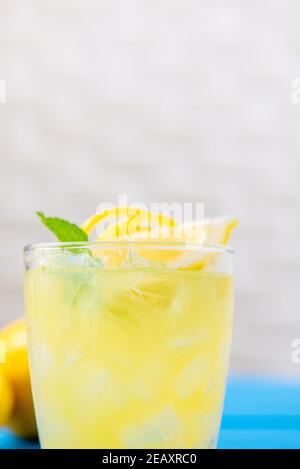 Nahaufnahme von frischem Limonadengetränk auf blauem Tisch mit Zitronen Und Minzblätter Stockfoto