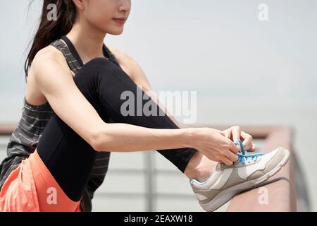 Junge asiatische Frau in Sportswear Schnürung vor dem Training Stockfoto