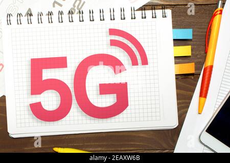 Notizbuch mit Notizen 5G auf dem Bürotisch mit Werkzeugen. Stockfoto