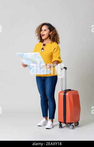 Junge erstaunt afroamerikanische Frau Tourist mit Koffer halten Welt Karte auf hellgrauem Studiohintergrund Stockfoto