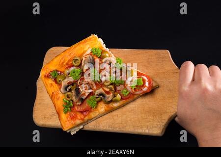 Servierscheibe Pizza auf Holzbrettplatte, isoliert auf schwarz mit Kopierplatz. Stockfoto