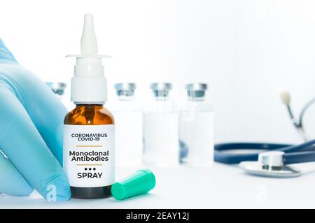 Arzt Halten Sie ein Fläschchen mit monoklonalen Antikörpern Nasenspray, eine neue Behandlung für Coronavirus Covid-19, auf einem weißen Tisch mit einigen Fläschchen und einem Stethoskop Stockfoto