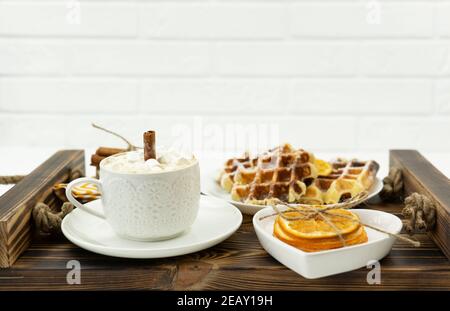 Frühes Frühstück Kaffee mit Marshmallows und einem Stock Zimt Und belgische Waffeln liegen auf einem Holztablett Stockfoto