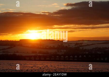 Seaton, Rutland, Großbritannien. 11th. Februar 2021. Wetter in Großbritannien. Die Sonne geht hinter dem Viadukt des Welland Valley auf, als die Temperatur in Großbritannien auf den niedrigsten Stand seit einem Jahrzehnt gesunken ist. Credit Darren Staples/Alamy Live News. Stockfoto