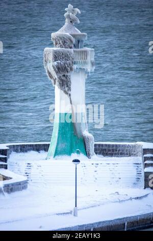 Sassnitz, Deutschland. Februar 2021, 11th. Der eisige Leuchtturm am Pier der Hafeneinfahrt. Frostiges Wetter und Schneefall behindern den Verkehr in Norddeutschland. Quelle: Jens Büttner/dpa-Zentralbild/dpa/Alamy Live News Stockfoto
