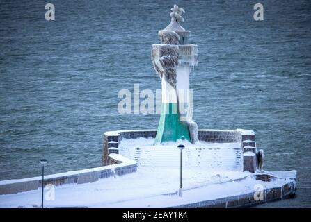 Sassnitz, Deutschland. Februar 2021, 11th. Der eisige Leuchtturm am Pier der Hafeneinfahrt. Frostiges Wetter und Schneefall behindern den Verkehr in Norddeutschland. Quelle: Jens Büttner/dpa-Zentralbild/dpa/Alamy Live News Stockfoto