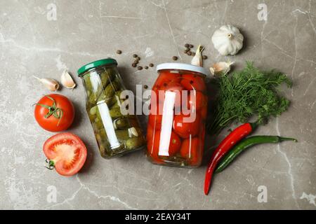 Gläser mit eingelegtem Gemüse und Zutaten auf grauem Hintergrund Stockfoto