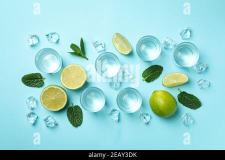 Schüsse, Limettenscheiben, Minze und Eiswürfel auf blauem Hintergrund, Draufsicht Stockfoto