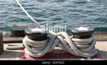 Geknotet auf metallischem Poller mit Sternen, Seefahrernhafen von San Diego, Kalifornien. Seeschiff im Dock vertäut. Kabelbinder am Span befestigt. Symbol Stockfoto