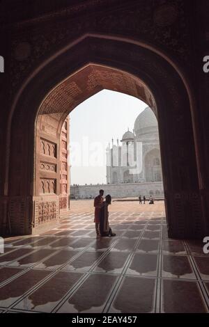 Romantisches Paar in der Nähe von Taj Mahal. Blick in schwarzer Bogensilhouette von der Moschee in Agra, Uttar Pradesh, Indien Stockfoto