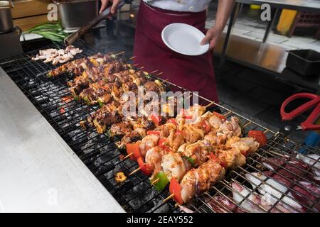 Der Koch bereitet Fleisch auf dem Grilltisch mit Rauch zu. Stockfoto