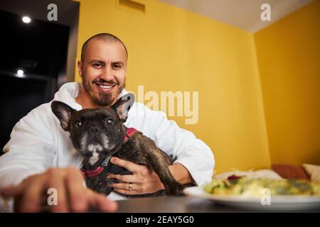 Fröhlicher Mann und seine französische Bulldogge posieren für die Kamera Stockfoto