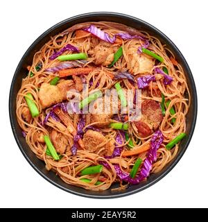 Pancit Bihon in schwarzer Schale isoliert auf weiß. Filipino Küche Nudeln Gericht mit Schweinebauch, Huhn, Gemüse. Asiatische Küche. Draufsicht Stockfoto