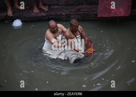 Kathmandu, Bagmati, Nepal. Februar 2021, 11th. Priester tauchen das Idol von Madhav Narayan und beten am Ufer des Bagmati Flusses während des Madhav Narayan Festivals im Pashupatinath Tempel in Kathmandu, Nepal am 11. Februar 2021. Das einmonatige Fest soll das Fasten beobachten und zur Göttin Swasthani und zum Gott Madhav Narayan für Wohlstand der Familienmitglieder beten. Quelle: Sunil Sharma/ZUMA Wire/Alamy Live News Stockfoto