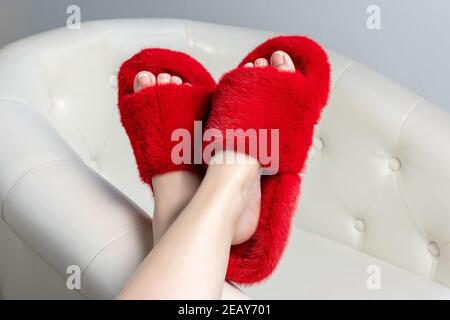 Schöne flauschige Fell Hausschuhe auf Frauen Beine. Stockfoto