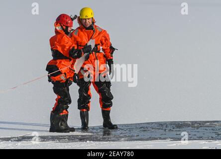 11. Februar 2021, Brandenburg, Potsdam: Charlotte Conrad (l.), Feuerwehrchefin, und Andy Hertel, Feuerwehrchefin der Potsdamer Berufsfeuerwehr, üben die Rettung eines im Eis eingestürzten Menschen. Am selben Tag hatte die Potsdamer Berufsfeuerwehr das aktuelle winterliche und kalte Wetter genutzt, um die Rettung von Menschen aus dem Eis und das Tauchen unter realen Bedingungen zu üben. Rund 20 Mitglieder der Berufsfeuerwehr und der Polizeiwache Babelsberg waren an dieser Übung im tiefen See am Steg der Schiffbauergasse beteiligt. Foto: Patrick Pleul/d Stockfoto