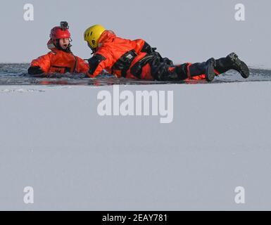 11. Februar 2021, Brandenburg, Potsdam: Charlotte Conrad (l.), Feuerwehrchefin, und Andy Hertel, Feuerwehrchefin der Potsdamer Berufsfeuerwehr, üben die Rettung eines im Eis eingestürzten Menschen. Am selben Tag hatte die Potsdamer Berufsfeuerwehr das aktuelle winterliche und kalte Wetter genutzt, um die Rettung von Menschen aus dem Eis und das Tauchen unter realen Bedingungen zu üben. Rund 20 Mitglieder der Berufsfeuerwehr und der Polizeiwache Babelsberg waren an dieser Übung im tiefen See am Steg der Schiffbauergasse beteiligt. Foto: Patrick Pleul/d Stockfoto