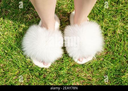 Schöne flauschige Fell Hausschuhe auf Frauen Beine. Stockfoto