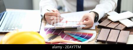 Designer im Büro sitzt am Tisch mit Projekt und einer Farbpalette für die Einrichtung Stockfoto
