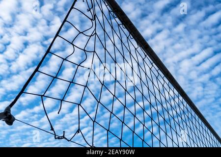 Tennis- oder Volleyballnetz gegen blauen Himmel. Wunderschöne Zirruswolken. Schöne Cirrus Wolken über dem Sportplatz Stockfoto