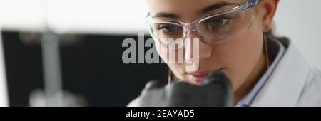 Chemiker in Brille und weißem Mantel schaut durch das Mikroskop Stockfoto