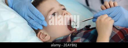Zahnärztin untersucht Kinderzähne mit Metallwerkzeugen Stockfoto