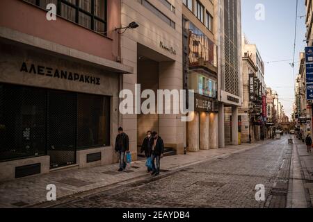 Athen, Griechenland. Februar 2021, 11th. Passanten gehen an geschlossenen Geschäften in der Haupteinkaufsstraße Ermou vorbei. Seit Donnerstagmorgen ist der Großraum Athen erneut einer harten Sperre ausgesetzt, um die Corona-Pandemie einzudämmen, deren Einhaltung von der Polizei mit zahlreichen Straßensperren durchgesetzt wird. Quelle: Angelos Tzortzinis/DPA/Alamy Live News Stockfoto