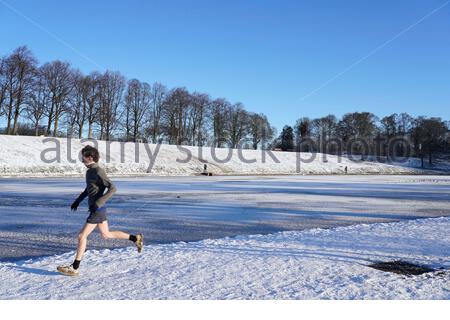 Edinburgh, Schottland, Großbritannien. Februar 2021, 11th. Menschen genießen Joggen durch den Park an einem herrlichen sonnigen, aber eiskalten Morgen in einem schneebedeckten Inverleith Park. Kredit: Craig Brown/Alamy Live Nachrichten Stockfoto