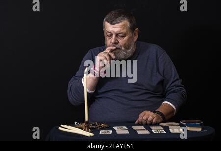 Schönes, dezernes Porträt eines älteren Mannes - Beleuchtung für Rutscher Eine Zigarre aus dem Kerzenlicht Stockfoto