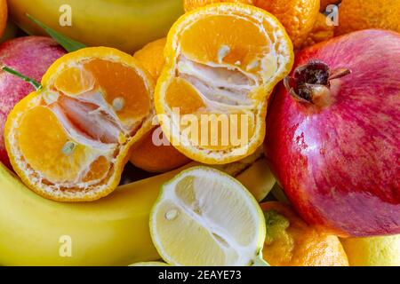 Verschiedene frische Früchte Anordnung von Bananen, Granatapfel, in Scheiben geschnittene Zitrone und in Scheiben geschnittene Mandarine. Stockfoto