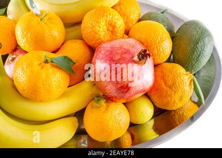 Verschiedene frische Obst- und Gemüseteller mit Bananen, Granatapfel, Zitrone, Mandarine und Avocado. Stockfoto