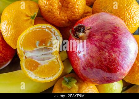 Verschiedene frische Früchte Anordnung von Bananen, Granatapfel, in Scheiben geschnittene Zitrone und in Scheiben geschnittene Mandarine. Stockfoto