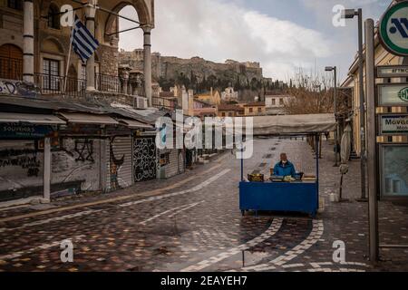 Athen, Griechenland. Februar 2021, 11th. Auf dem leeren Monastiraki-Platz unterhalb der Akropolis wartet ein Obsthändler auf die Kunden. Seit Donnerstagmorgen ist der Großraum Athen erneut einer harten Sperre ausgesetzt, um die Corona-Pandemie einzudämmen, wobei die Polizei die Einhaltung zahlreicher Straßensperren durchgesetzt hat. Quelle: Angelos Tzortzinis/DPA/Alamy Live News Stockfoto