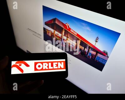 Person, die Mobiltelefon mit dem Logo des polnischen Öl- und Gasunternehmens PKN Orlen auf dem Bildschirm vor der Business-Website hält. Konzentrieren Sie sich auf das Smartphone-Display. Stockfoto