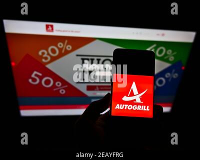 Person, die Smartphone mit Logo der italienischen Catering-Firma Autogrill S.p.A. auf dem Bildschirm vor der Website hält. Konzentrieren Sie sich auf die Telefonanzeige. Stockfoto