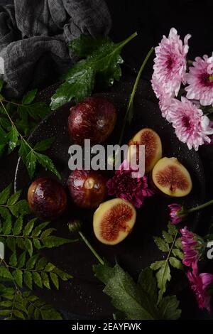Rohe frische Feigenfrüchte auf dunklem Hintergrund. Scheiben frischer gewöhnlicher Feige (Ficus carica) Stockfoto