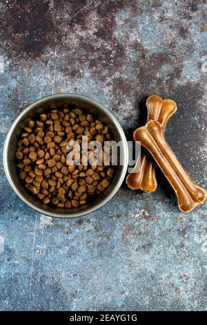 Vertikale Aufnahme einer Schüssel mit Hundefutter und zähig Knochen auf einer rauen Oberfläche Stockfoto