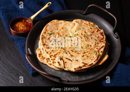 Food Konzept Spot Fokus hausgemachte Paratha, Parotta oder Porotta geschichteten Fladenbrot auf schwarzem Hintergrund mit Kopierraum Stockfoto