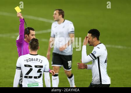 Schiedsrichter Peter Bankes zeigt eine gelbe Karte und Bücher Ben Cabango von Swansea Stadt nach einem Foul auf Ilkay Gundogan von Manchester City . The Emirates FA Cup, 5th Round Match, Swansea City gegen Manchester City im Liberty Stadium in Swansea, South Wales am Mittwoch, 10th. Februar 2021. Dieses Bild darf nur für redaktionelle Zwecke verwendet werden. Nur redaktionelle Verwendung, Lizenz für kommerzielle Nutzung erforderlich. Keine Verwendung in Wetten, Spiele oder ein einzelner Club / Liga / Spieler Publikationen. PIC von Andrew Orchard / Andrew Orchard Sport Fotografie / Alamy Live News Stockfoto