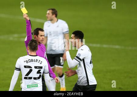 Schiedsrichter Peter Bankes zeigt eine gelbe Karte und Bücher Ben Cabango von Swansea Stadt nach einem Foul auf Ilkay Gundogan von Manchester City . The Emirates FA Cup, 5th Round Match, Swansea City gegen Manchester City im Liberty Stadium in Swansea, South Wales am Mittwoch, 10th. Februar 2021. Dieses Bild darf nur für redaktionelle Zwecke verwendet werden. Nur redaktionelle Verwendung, Lizenz für kommerzielle Nutzung erforderlich. Keine Verwendung in Wetten, Spiele oder ein einzelner Club / Liga / Spieler Publikationen. PIC von Andrew Orchard / Andrew Orchard Sport Fotografie / Alamy Live News Stockfoto