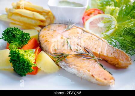 Gebratene Lachssteaks mit Gemüse auf dem Teller. Stockfoto