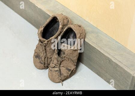 Schmutzige, getrocknete schlammige und unordentliche Sneaker-Schuhe, mit denen sie total bedeckt sind Schlamm sieht unerkennbar aus Stockfoto