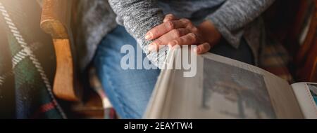 Nahaufnahme unkenntlich Frau hält ein Fotoalbum auf dem Sofa sitzen. Memories-Konzept. Stockfoto